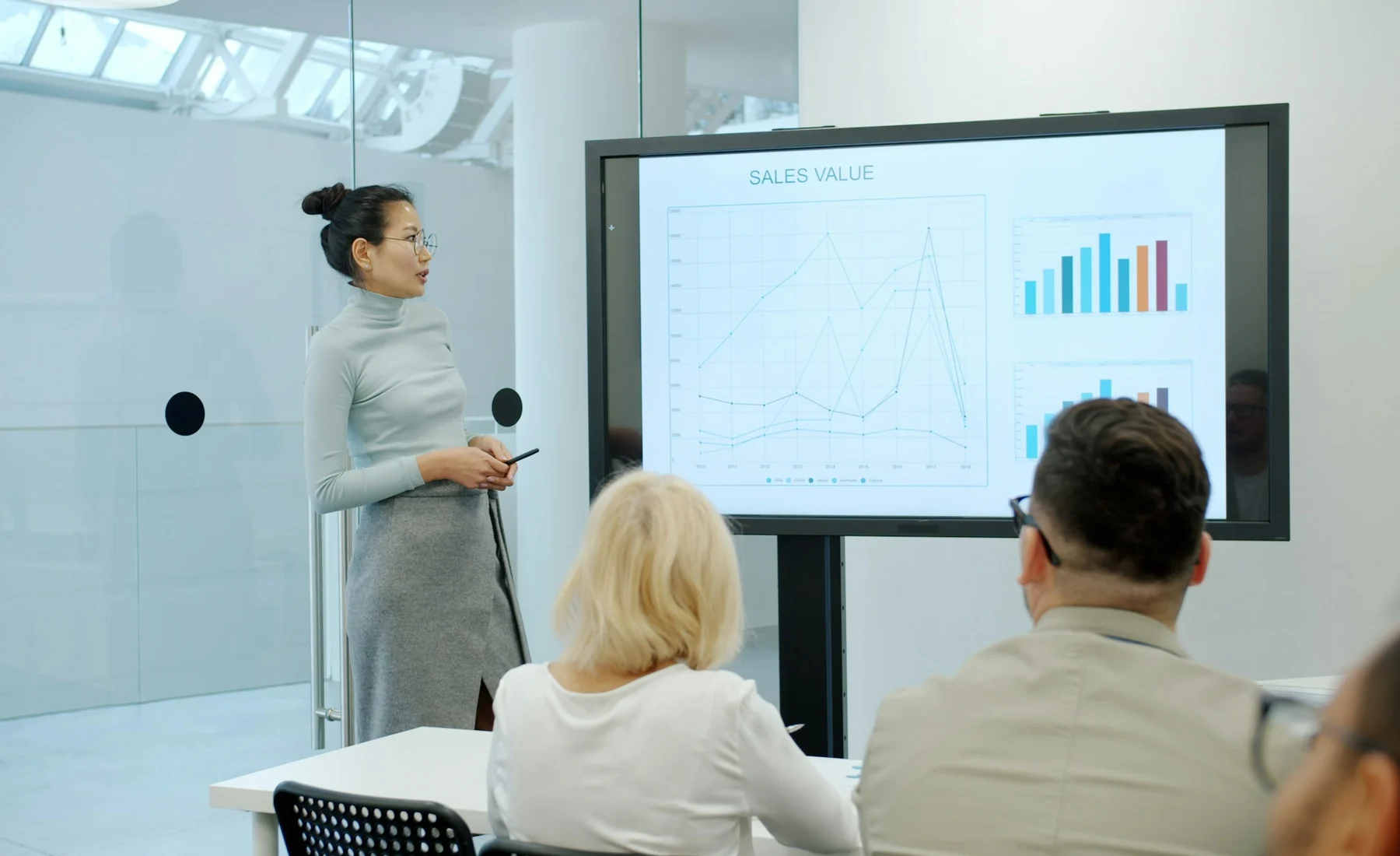 An East Asian business presenter explaining financial charts to an audience